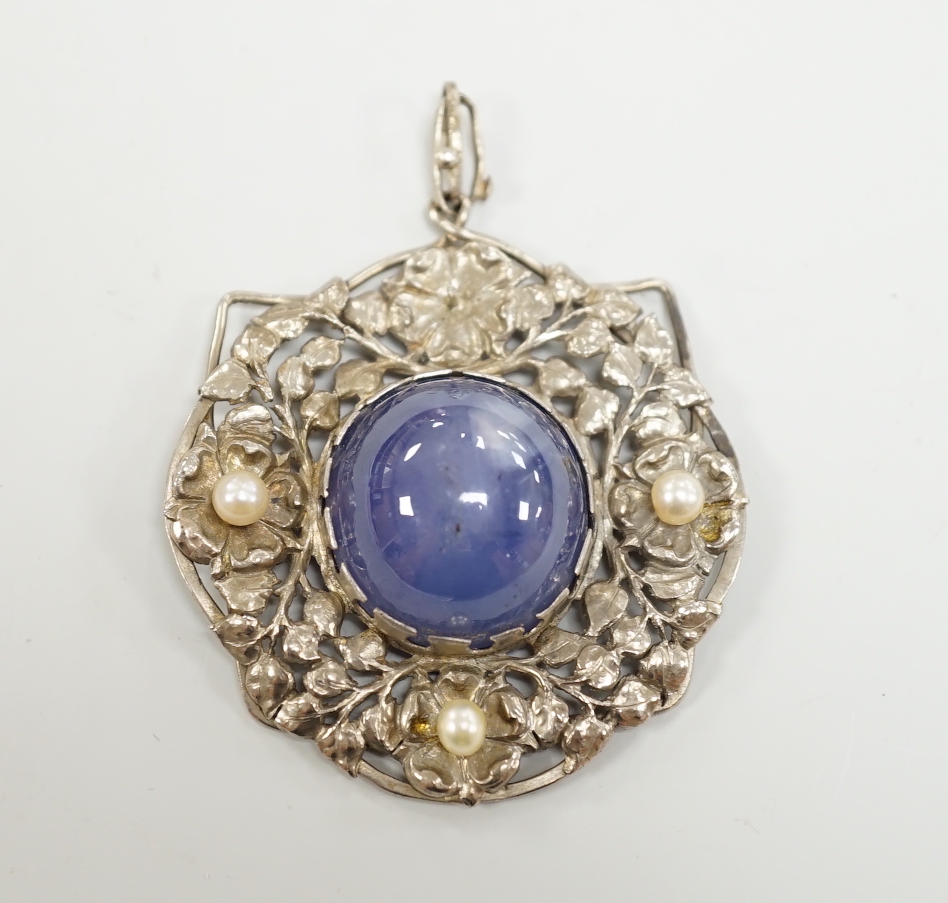 An early 20th century continental pierced white metal, cabochon star sapphire and cultured pearl set circular pendant, diameter 46mm.
